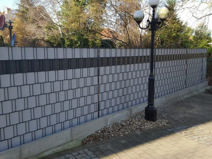 Doppelstabmattenzaun mit hellen Sichtschutzstreifen und dunklem Zierband entlang einer Hofeinfahrt