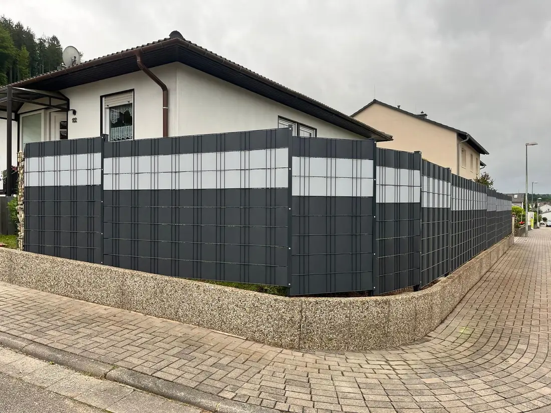 Doppelstabmattenzaun mit Sichtschutzstreifen um ein komplettes Eckgrundstück in Waldfischbach-Burgalben, gesetzt auf eine bestehende Mauer
