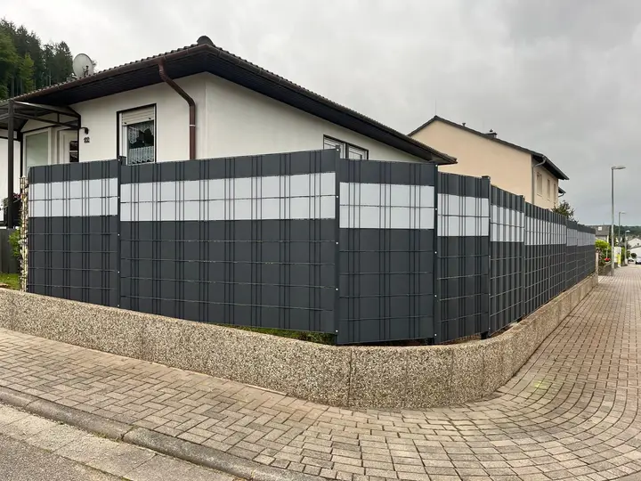 Doppelstabmattenzaun mit Sichtschutzstreifen um ein komplettes Eckgrundstück, gesetzt auf eine bestehende Mauer