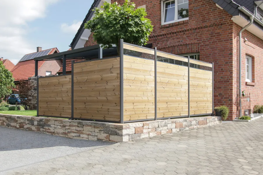 ThermoHolz-Sichtschutz mit dunklen Metallpfosten und schmalen Dekoreinsätzen um eine Terrasse auf einer Natursteinmauer