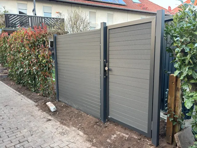 WPC-Steckzaun in Holzoptik mit zweiflügeligem WPC-Tor an einer Grundstückszufahrt in Ötigheim